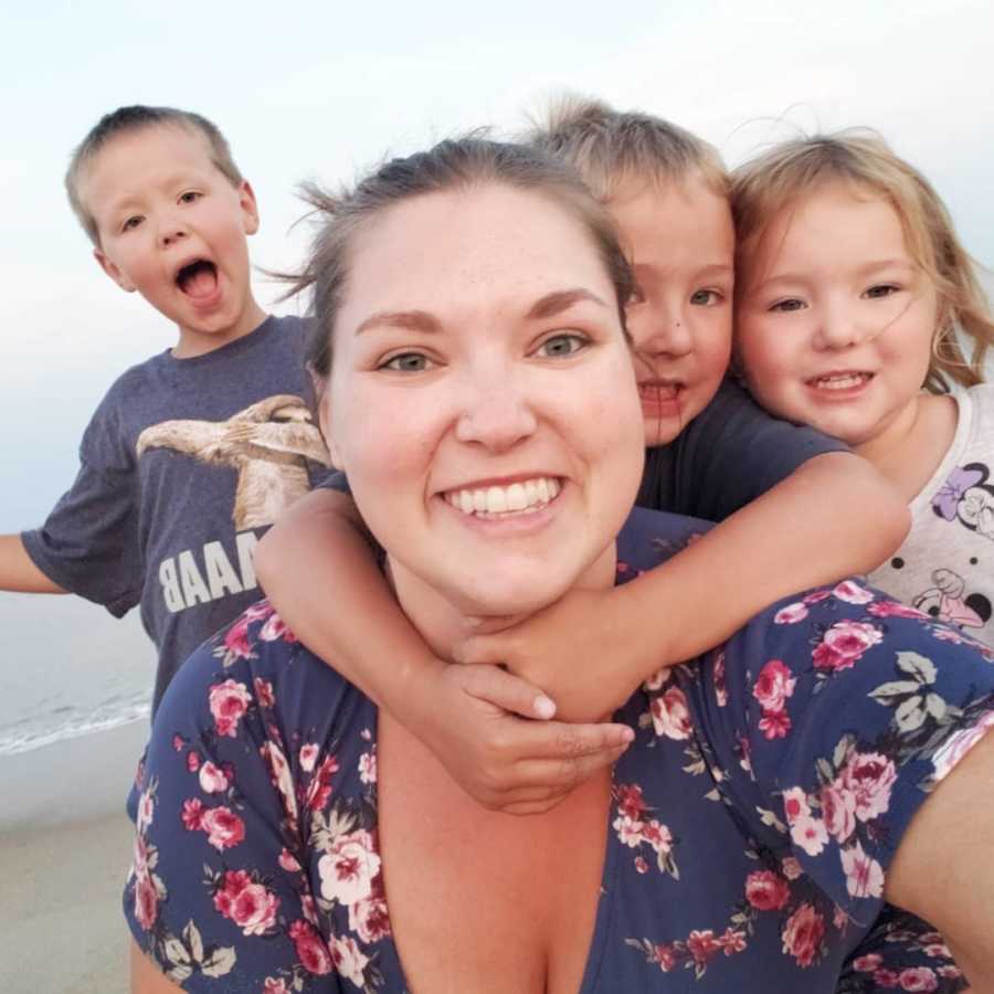 Widow smiles in selfie with her three children and ocean in background