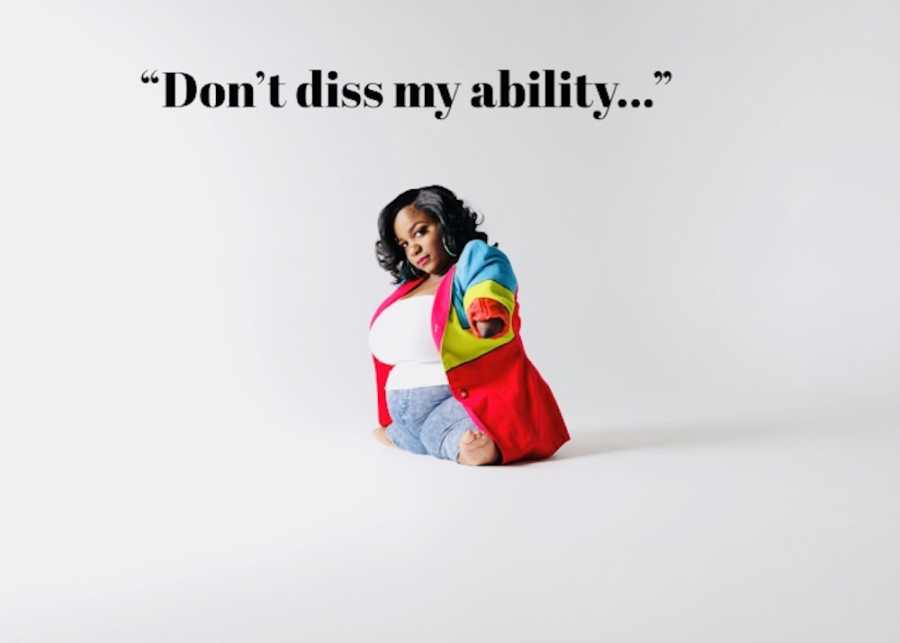 Woman without bottom half of arms sits on ground in rainbow blazer for photoshoot that says, "Don't diss my ability"