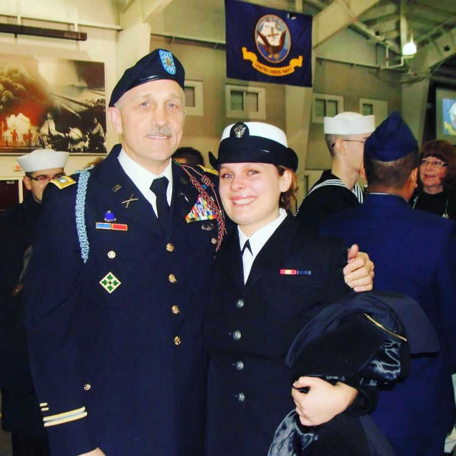 Woman in Navy stands smiling beside father who is also in the Navy
