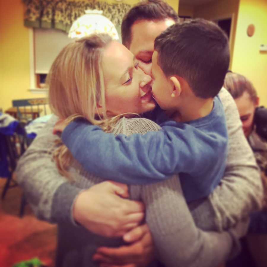 Man stands in home hugging his fiancee and his son