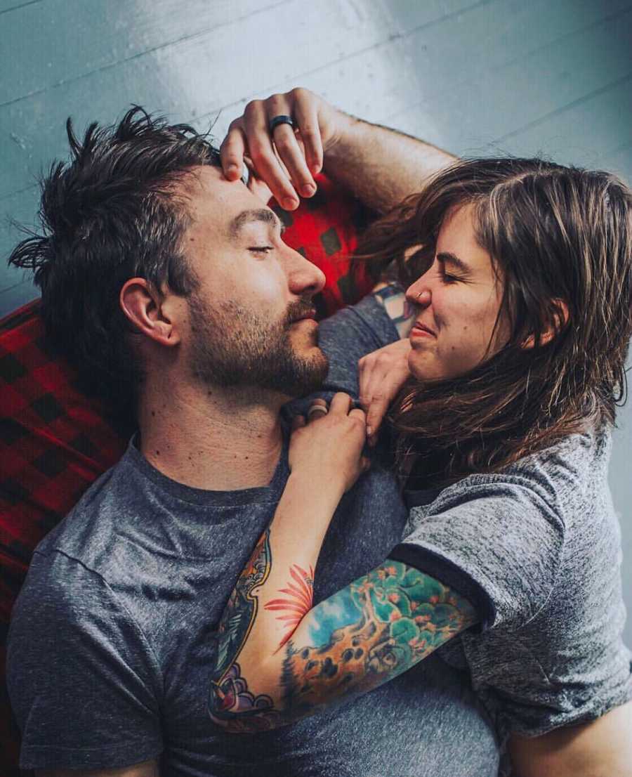 Husband lays on the ground on his back while his wife lays on her stomach beside him