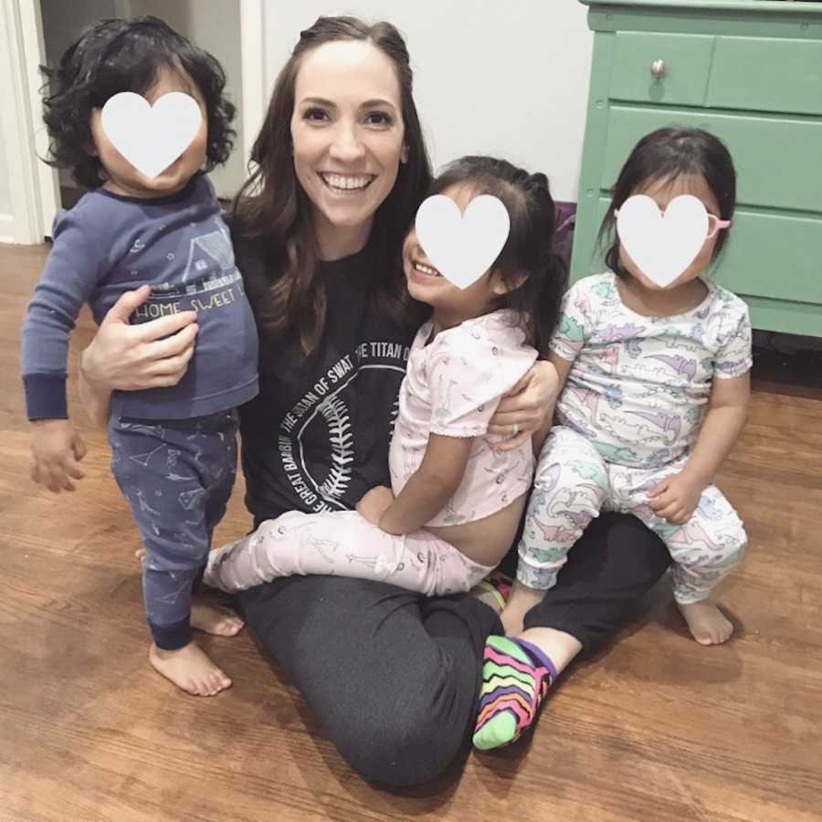 Woman sits on ground smiling with her three foster daughters