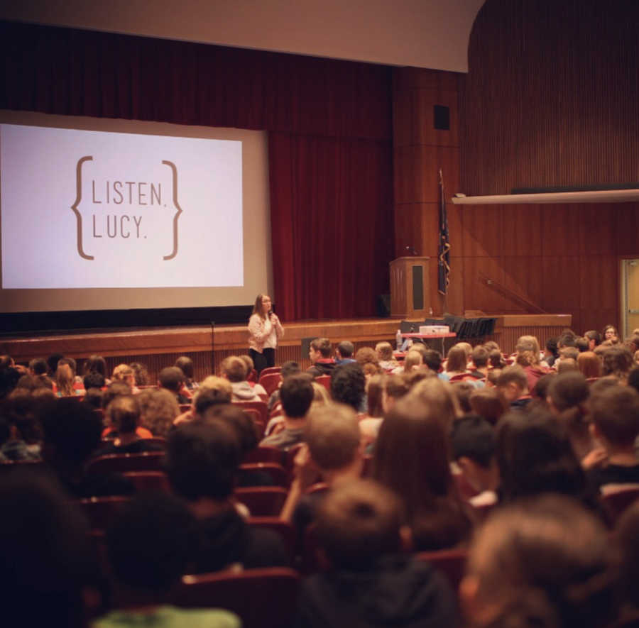 Woman who struggles with mental illness stands in front of auditorium speaking 