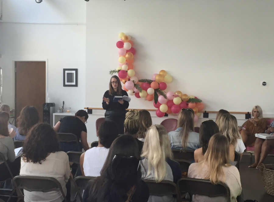 Woman who suffers from mental illness stands speaking in front of room full of people