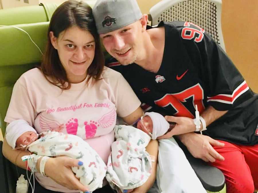 Mother sits in NICU holding newborn twins while her husband sits beside her