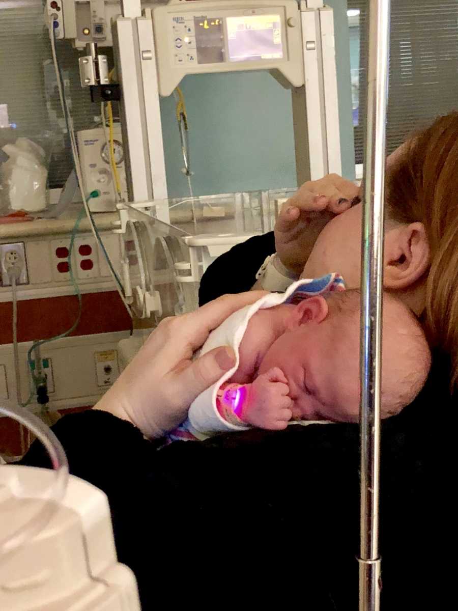 Mother cries as she sits in NICU holding newborn daughter to her chest