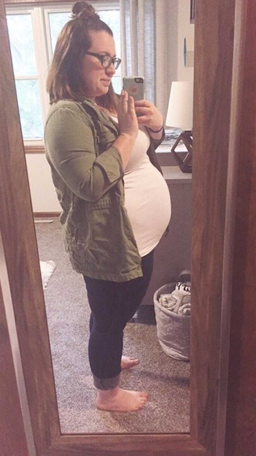 Pregnant woman who had a few miscarriages stands taking mirror selfie in home