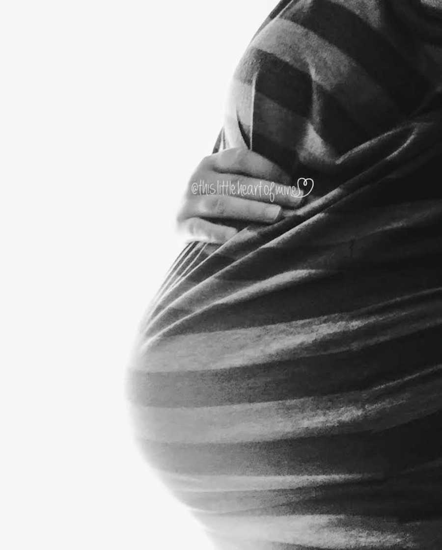 Close up of pregnant woman holding her stomach in striped shirt