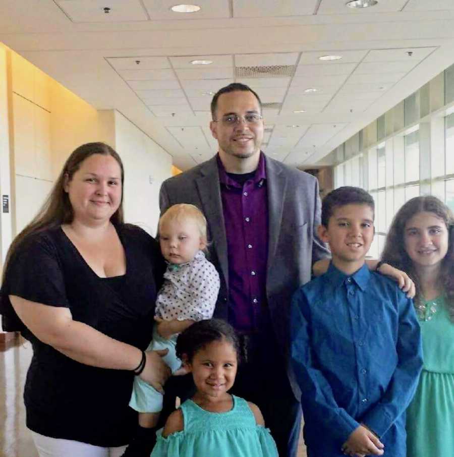 Husband and wife stand with their four adopted children 