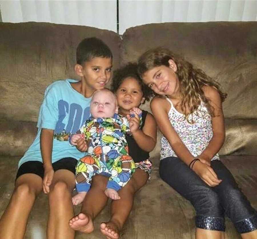 Four young children in foster care sit on couch