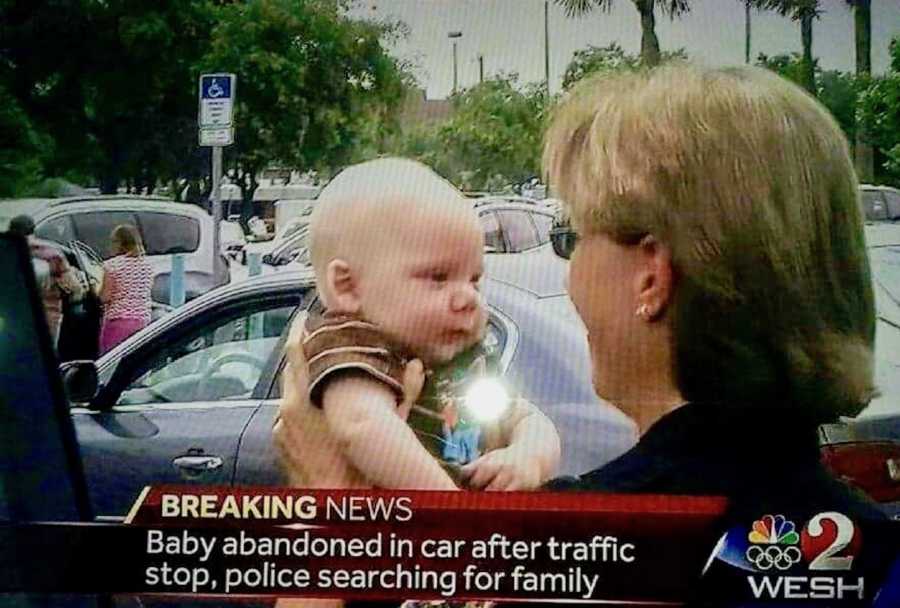 Screenshot of television news report of woman holding baby who was abandoned in parking lot