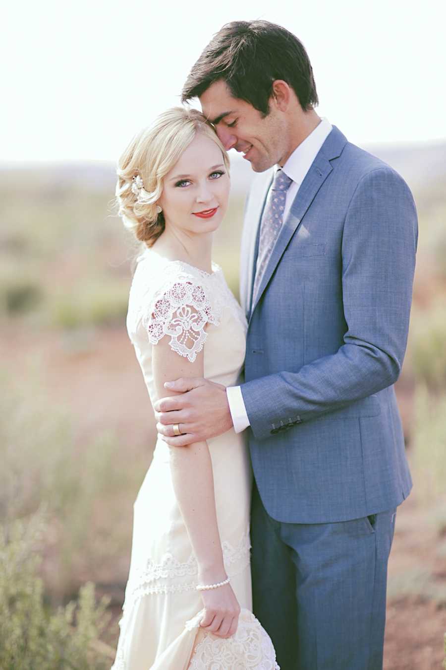 Bride and groom stand outside in field for photoshoot