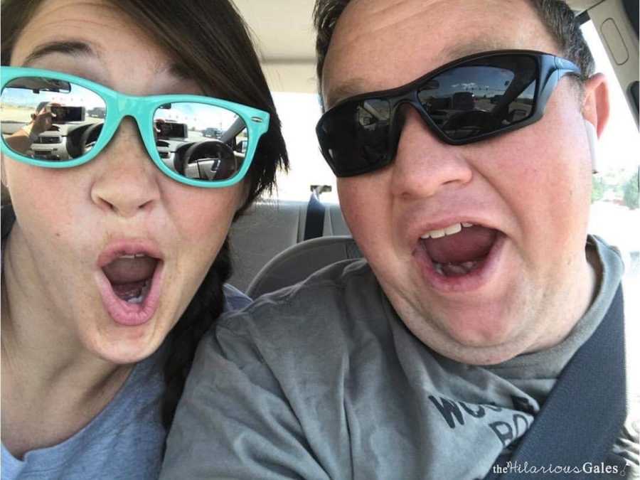 Husband and wife make silly faces in their car as they take selfie