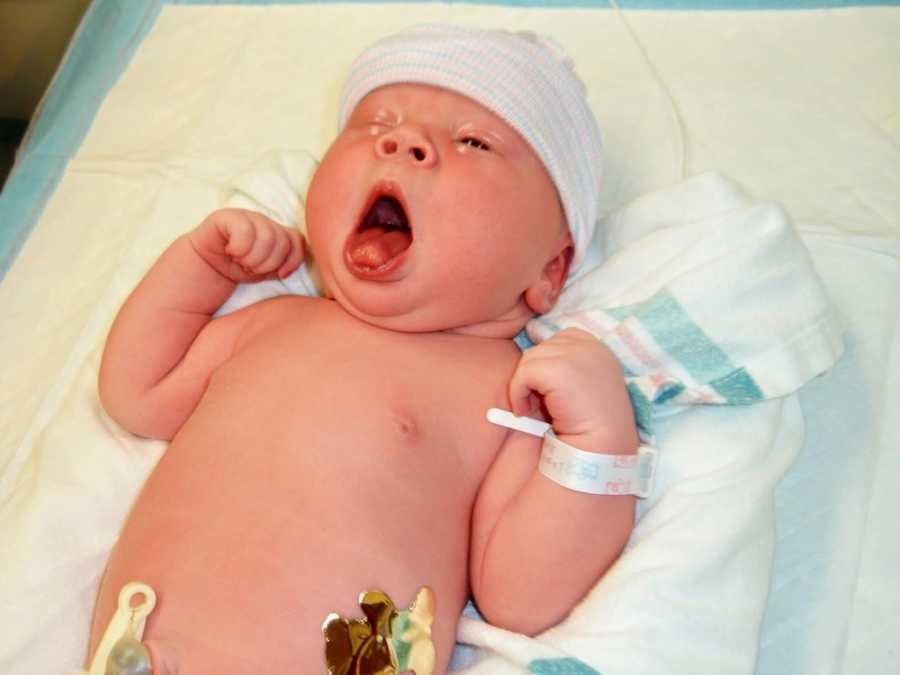 Newborn boy lay on his back yawning who will be adopted by two men