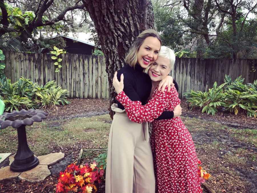 Woman who is back on her medication stands smiling in backyard as she hugs her sister