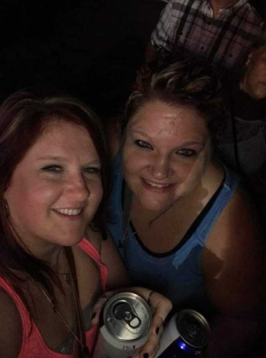 Woman smiles in selfie with friends as they hold beers at concert before shooting