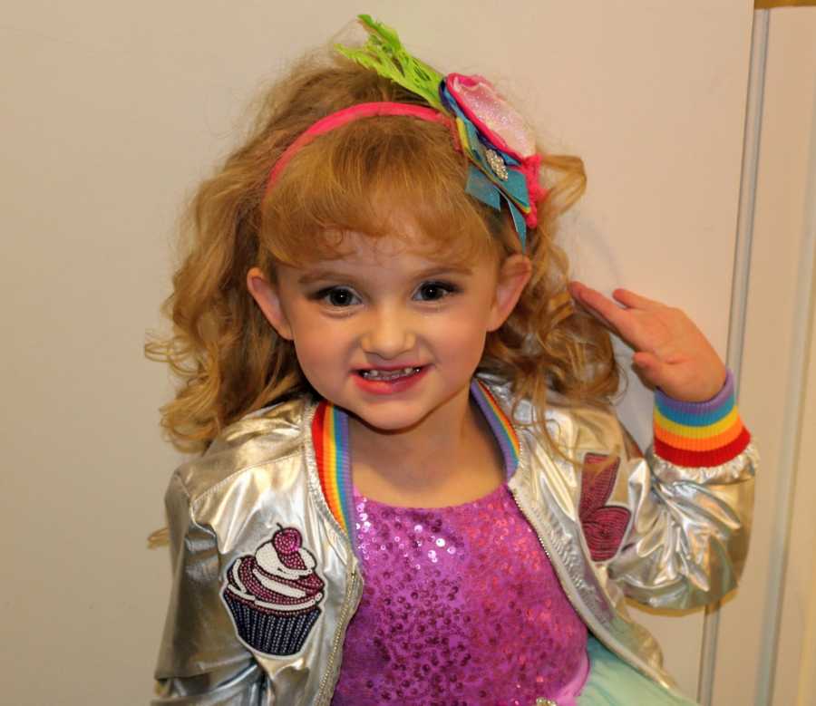 Little girl with Osteogenesis Imperfecta stands in costume and makeup for singing performance