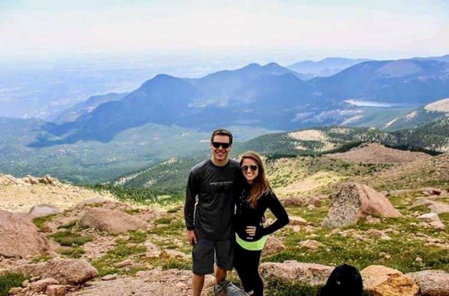 Boyfriend and girlfriend who received kindness from stranger stand smiling with mountains in background