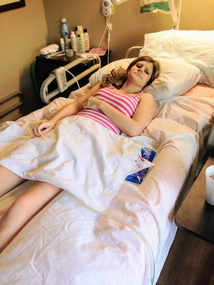 Woman with Crohn's and perenial disease lays in hospital bed with sad look on her face
