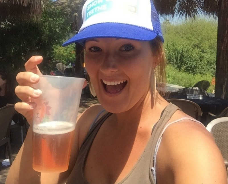 Mother smiles as she holds up glass of beer
