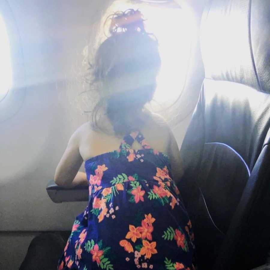 Little girl who acted terribly on plane sits in seat looking out of window