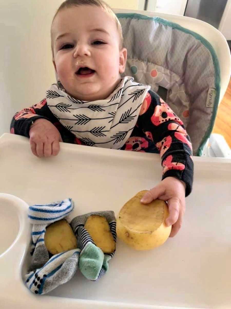 Baby sits in high chair where his socks lay with potatoes on them