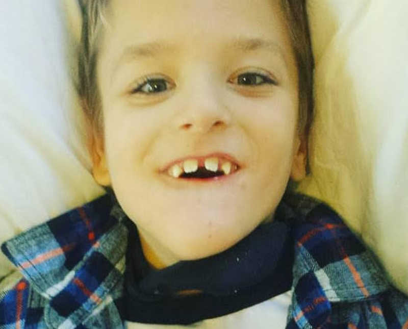 Little boy with cerebral palsy lays on back smiling