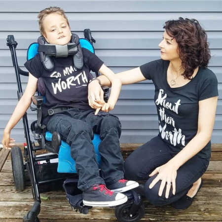Mother kneels beside son with cerebral palsy who sits in wheelchair 