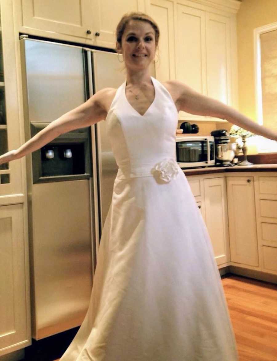 Woman stands in her wedding dress in her kitchen