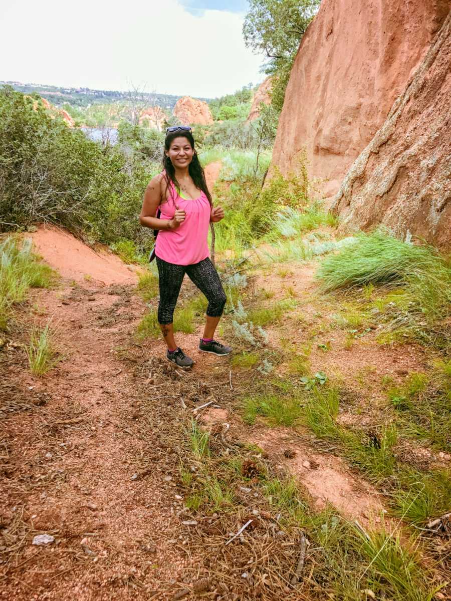 Woman who was abused by brother stands smiling outside near canyon