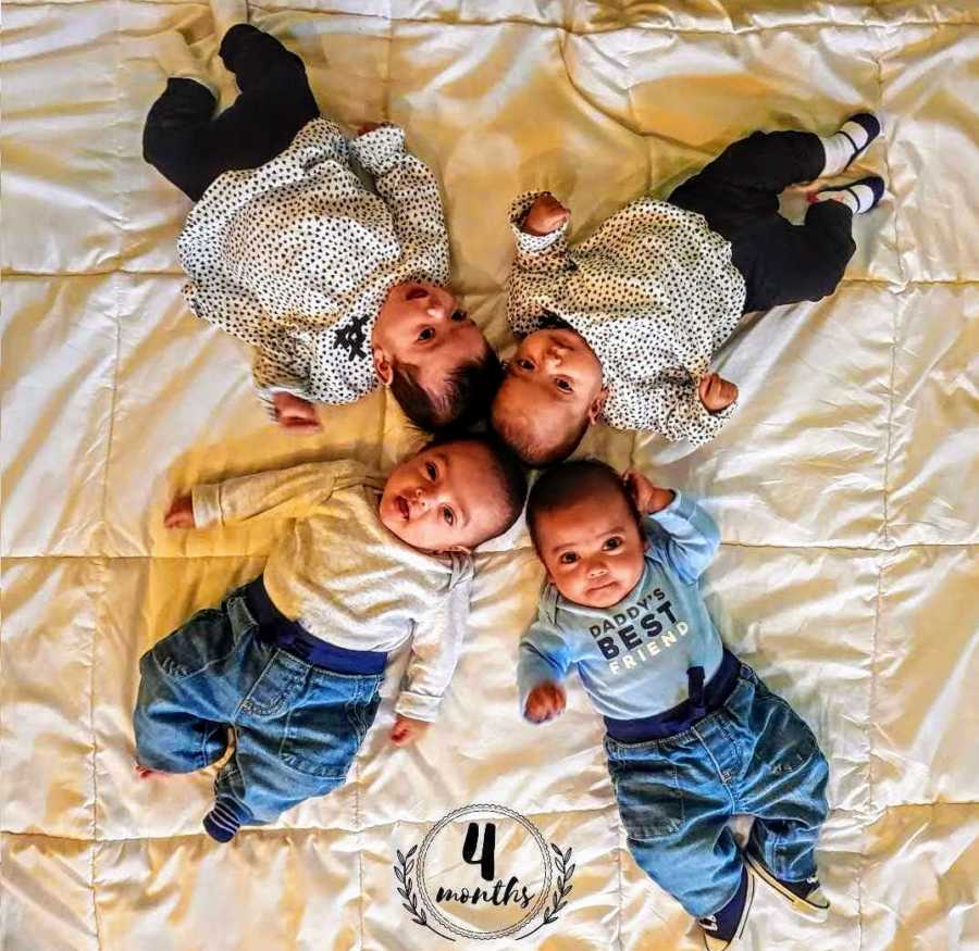 Quadruplet babies lay on their back in circle with their heads touching