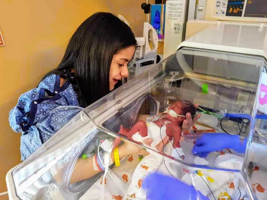 Woman smiles as she holds intubated newborn in NICU