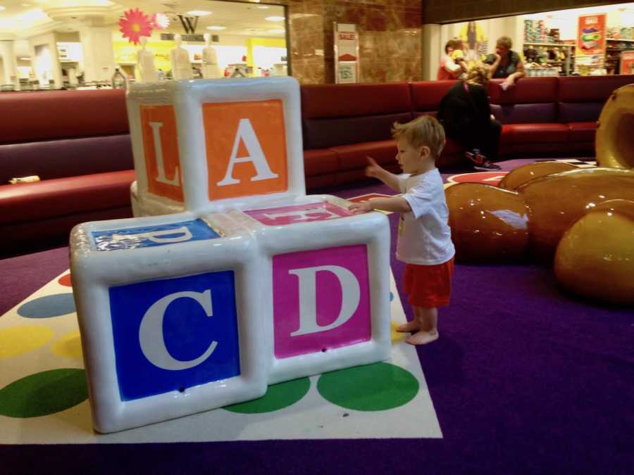 Little boy with autism stands in pay area of mall