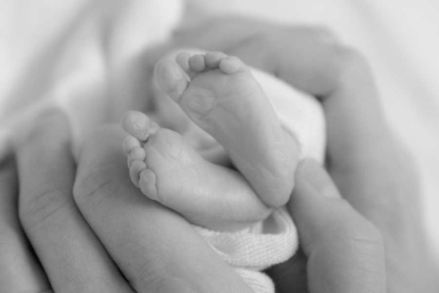 Close up of newborn's feet in hand of parents