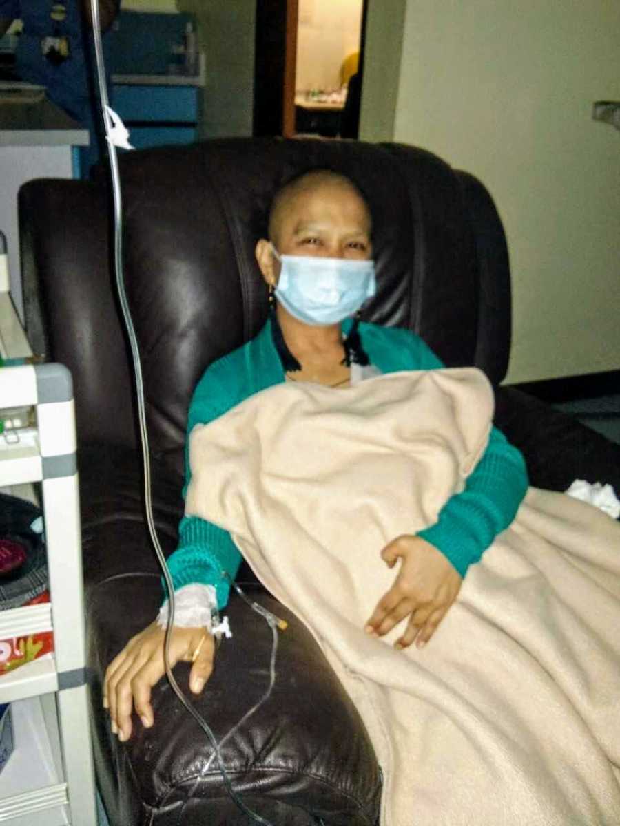 Woman with ovarian cancer sits in chair in home hooked up to IV machine