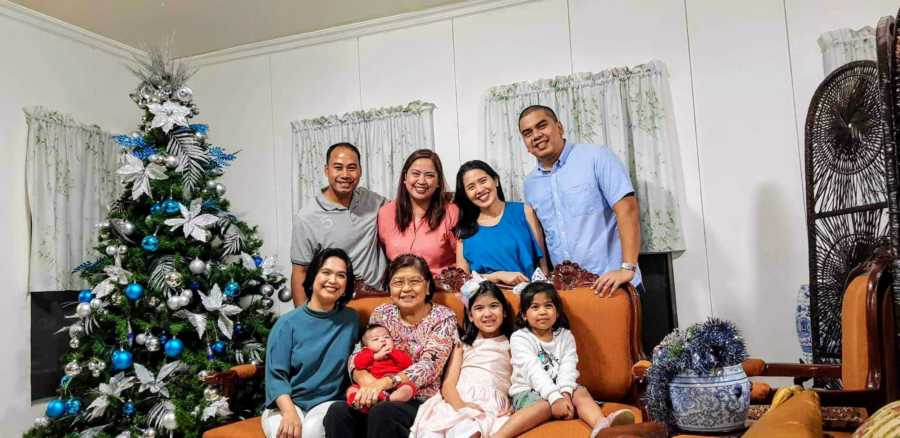 Woman who beat cancer sits with family in home beside Christmas tree