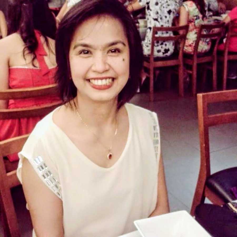 Woman who survived cancer sits smiling at restaurant table