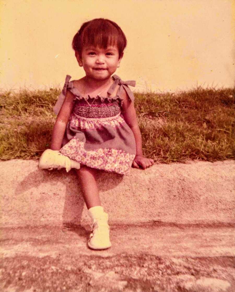 Little girl sits smiling on curb