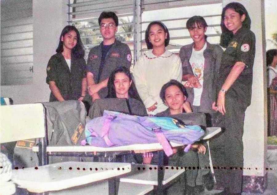 Young girl with cerebral palsy stands smiling beside her classmates