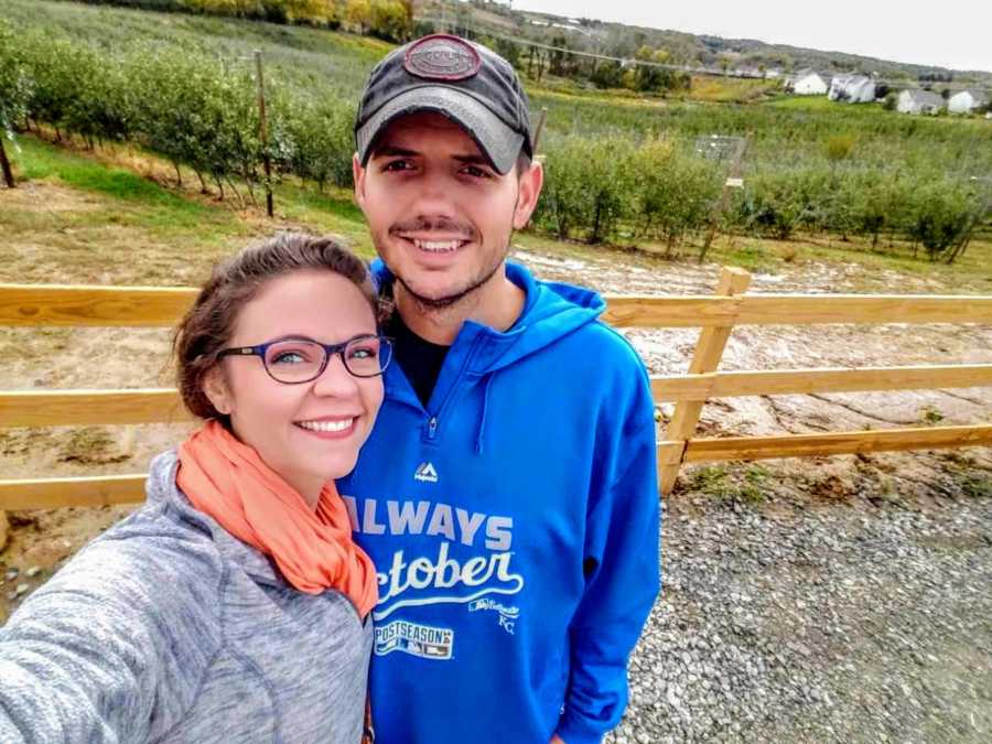 Woman who was named after her grandmother stands smiling outside beside vineyard with husband