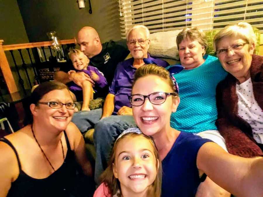 Woman smiles in selfie with her family in background including her grandmother she was named after