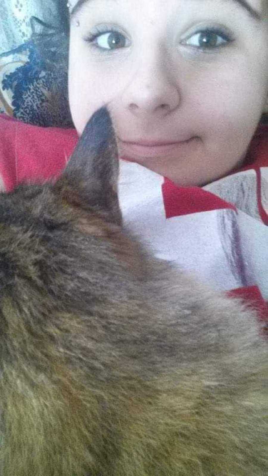Woman who struggles with OCD smiles in selfie with cat on her lap
