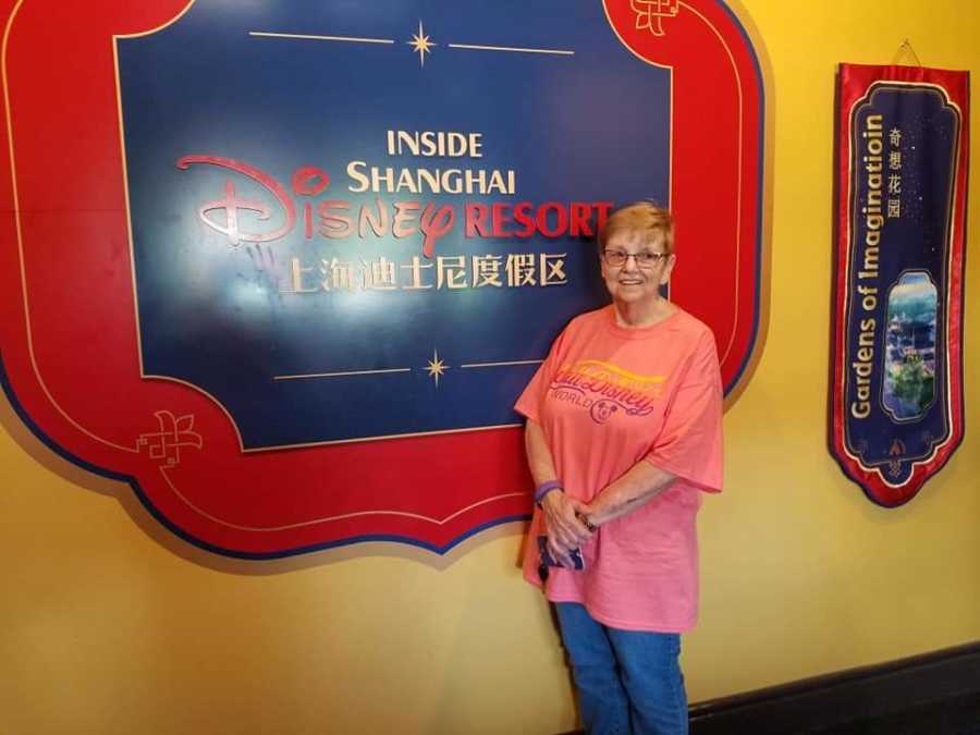 Woman who has since passed from ovarian cancer stands in front of Disney Resort sign