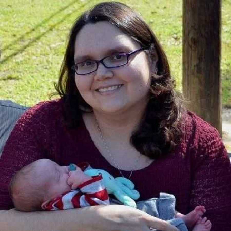 Woman who survived ovarian cancer smiles as she holds her newborn