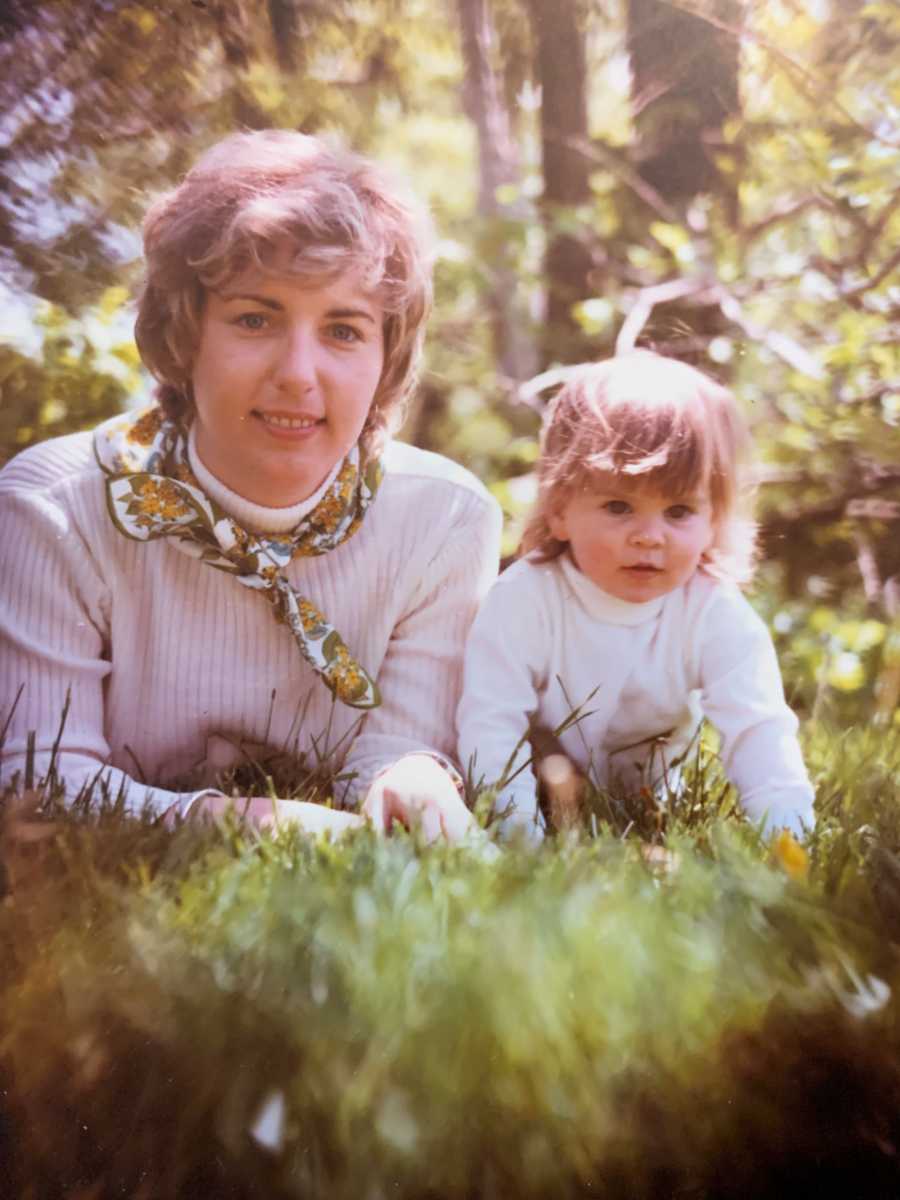 Little girl lays in grass beside her adopted mother