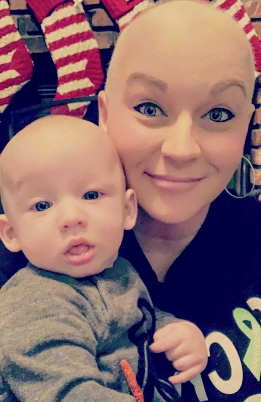Mother with Hodgkin's lymphoma and shaved head smiles in selfie with her baby boy