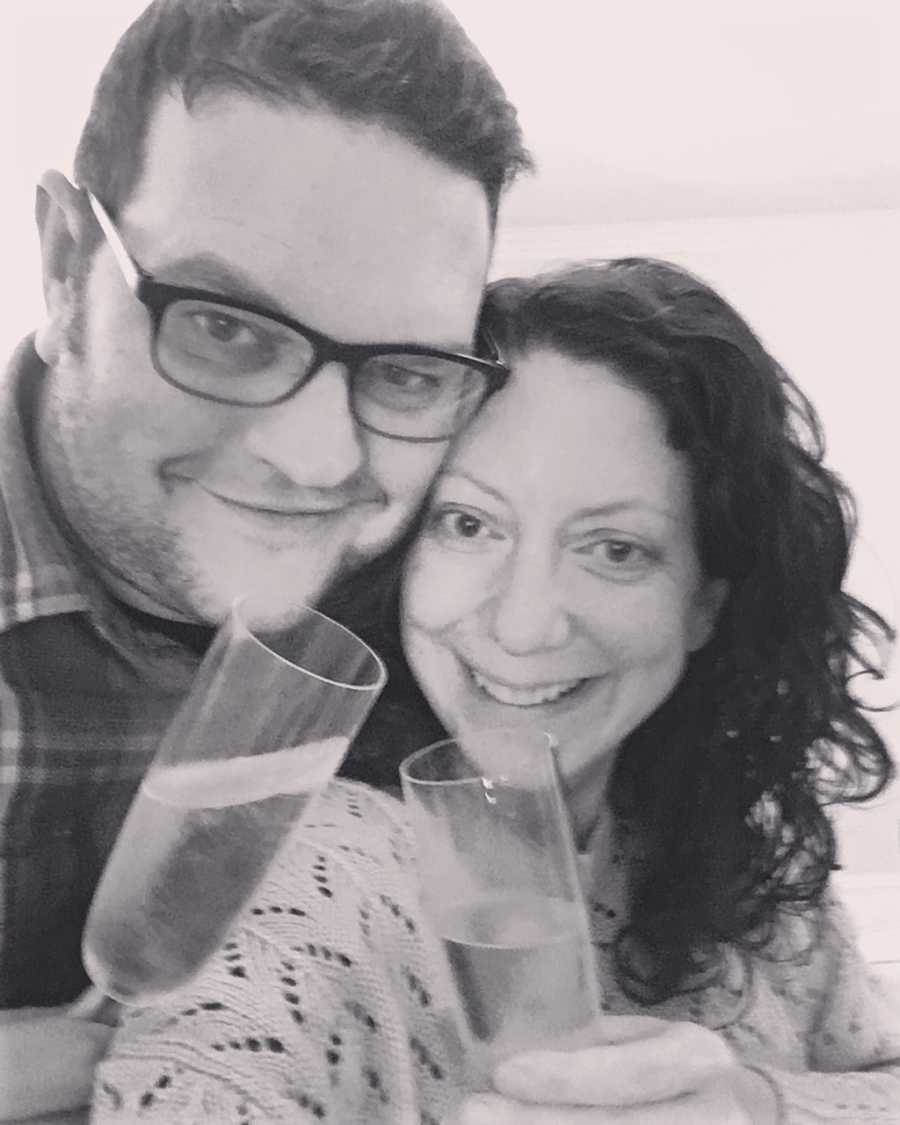 Husband and wife smile in selfie as they cheers with champagne flutes