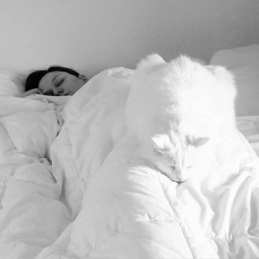 Woman who says life without a baby is also tiring lays asleep in bed with cat on top of her