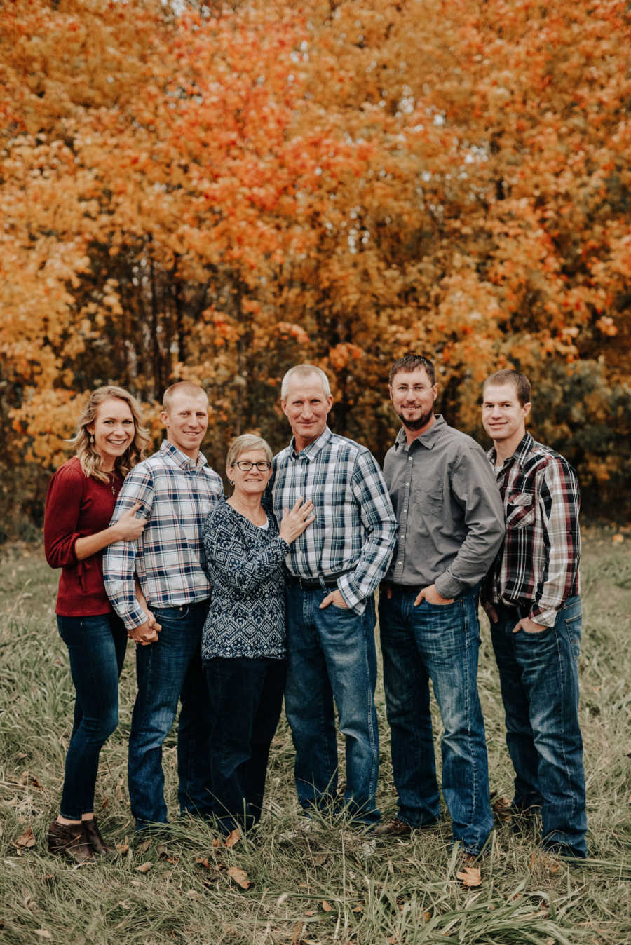 Woman stands in yard outside beside husband, mom, dad and two of her brothers