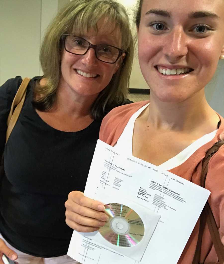 Young woman with MALS smiles in selfie while holding paper and CD beside her mother